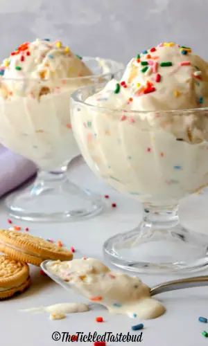 Two glass bowls of ice cream with sprinkles and cookies.