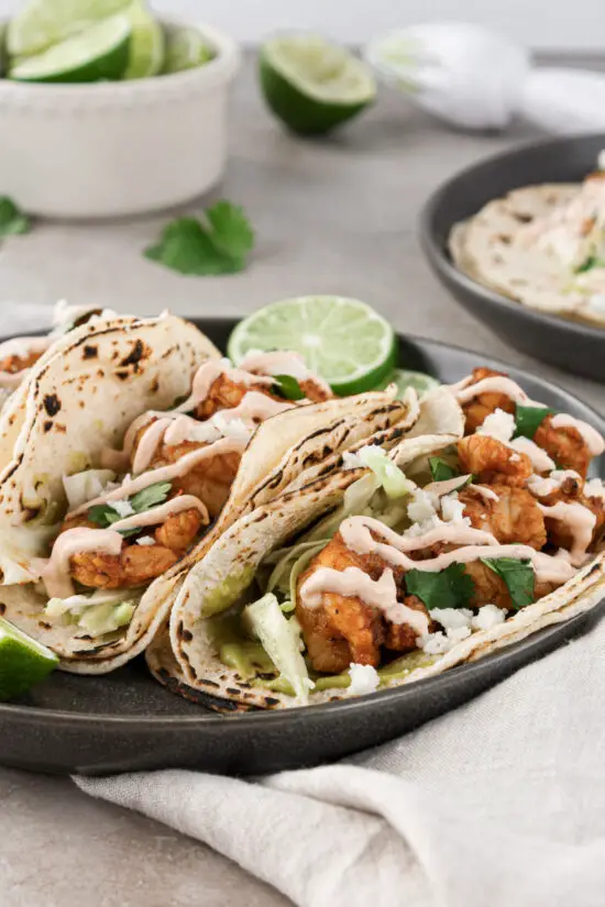 Shrimp tacos with fresh lime slices and cilantro leaves.