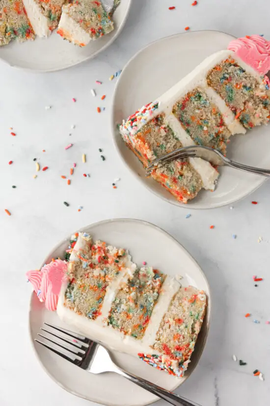 Slices of gluten-free funfetti cake on plates with forks.