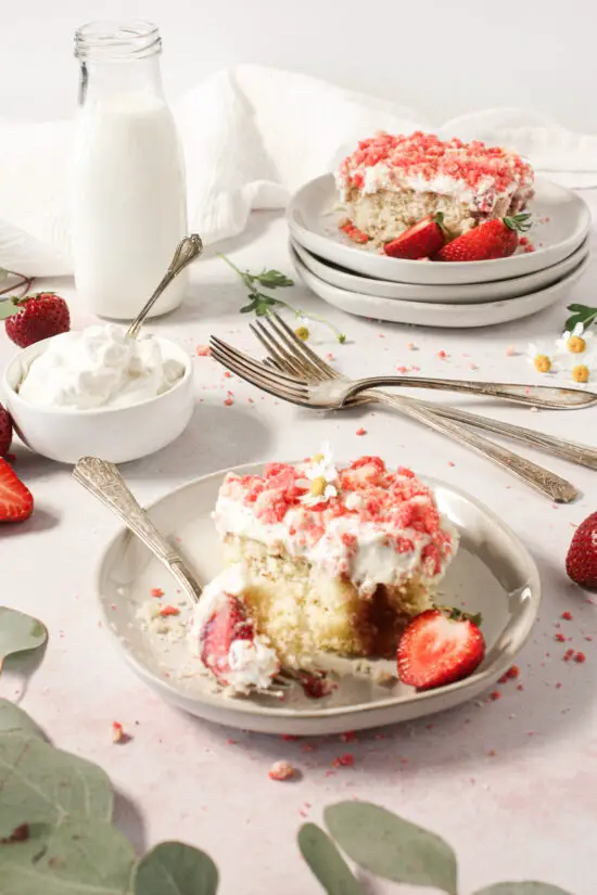 Slices of strawberry shortcake on plates with whipped cream.