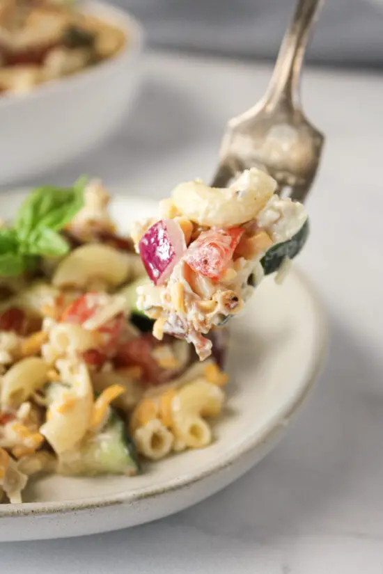 Up close picture of fork with bacon chicken ranch pasta salad on it.