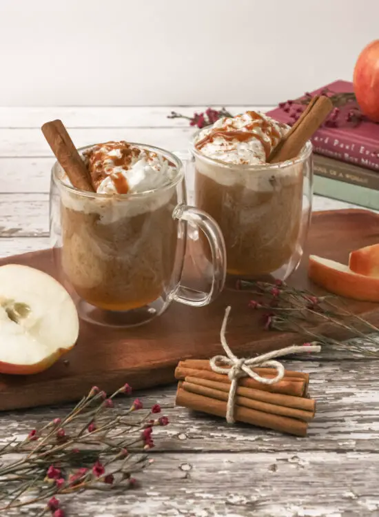 Two mugs filled with Creamy Caramel Apple Cider with cinnamon sticks.