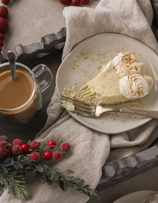 Slice of Eggnog Pie on a plate with fork and cup of brew next to it. 