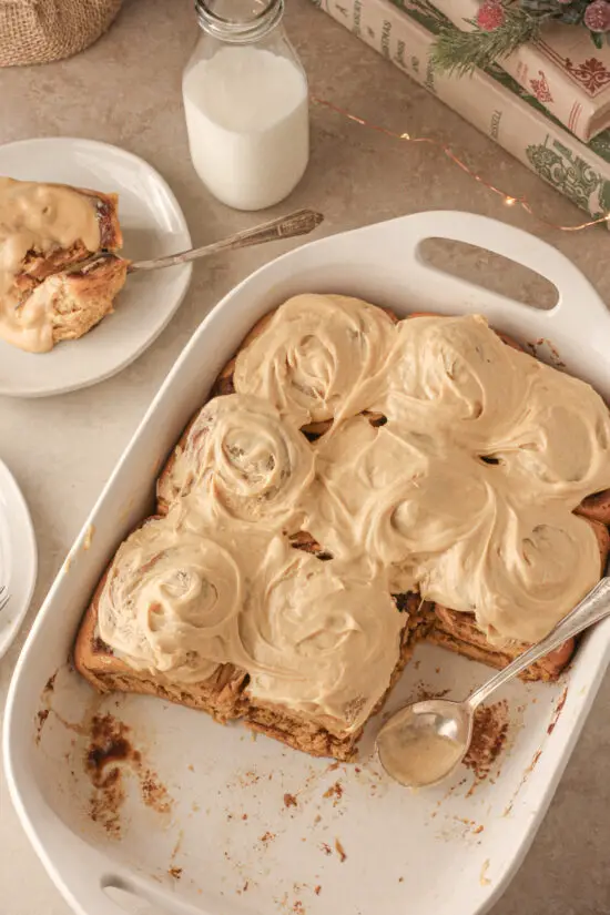 A white casserole dish with pan full of gingerbread cinnamon rolls.