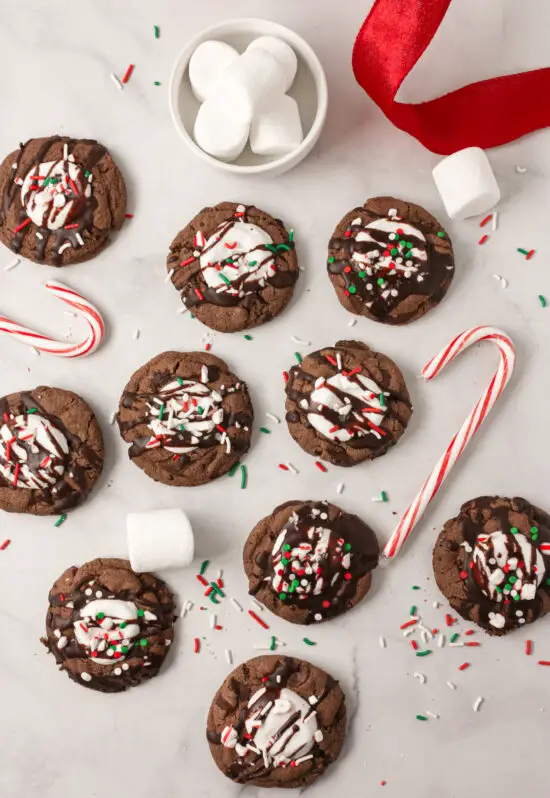 Hot chocolate cookies scattered around with marshmallows and candy canes. 