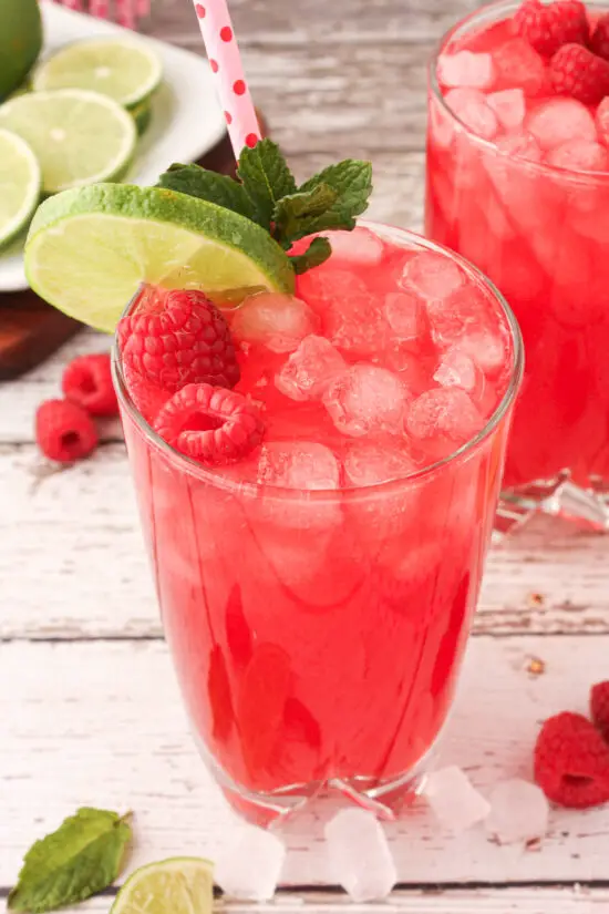 Glass cup of fresh Raspberry Limeade with ice and fresh raspberries. 