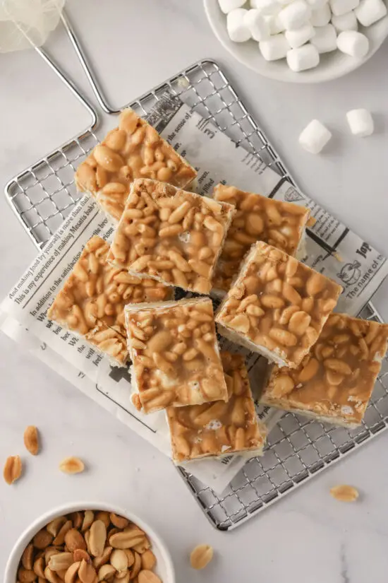 Tray filled with cut pieces of Peanut Marshmallow Bars with peanuts and mini marshmallows around.