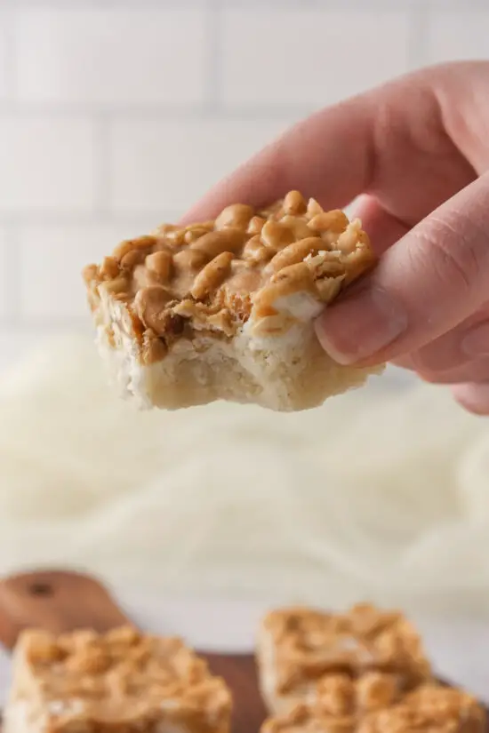 Hand holding a Peanut Marshmallow Bar with bite taken out of side. 