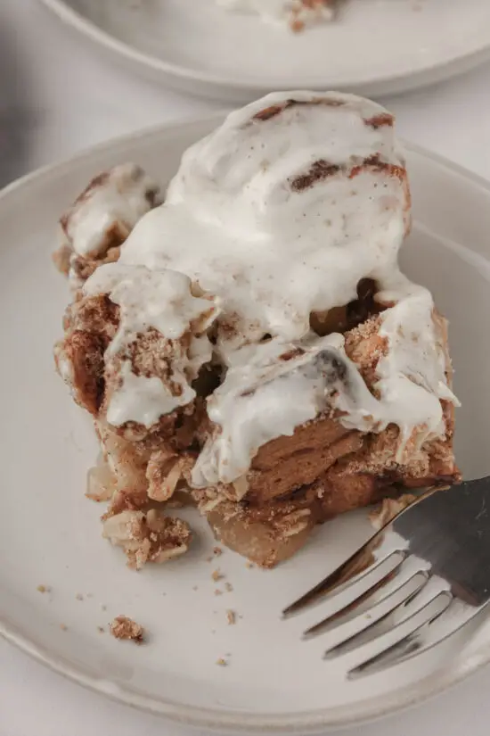 Single slice of Apple Cinnamon Roll Casserole with fork on a plate.