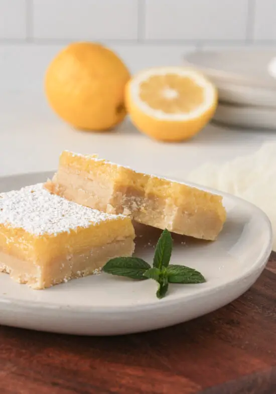 Two Paula Deen Lemon Bars on a plate with bite taken out.  