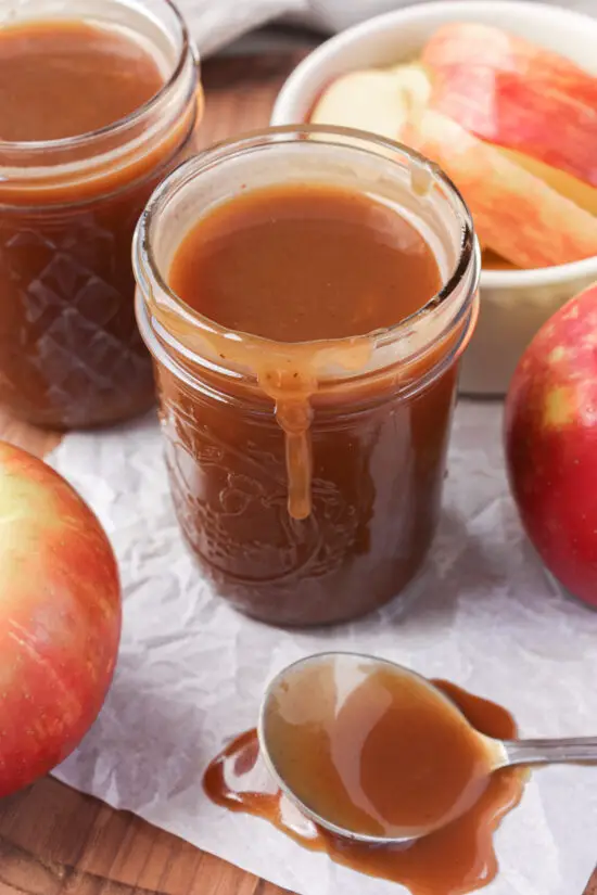 Glass jar filled with Brown Sugar Caramel Sauce dripping down the side.