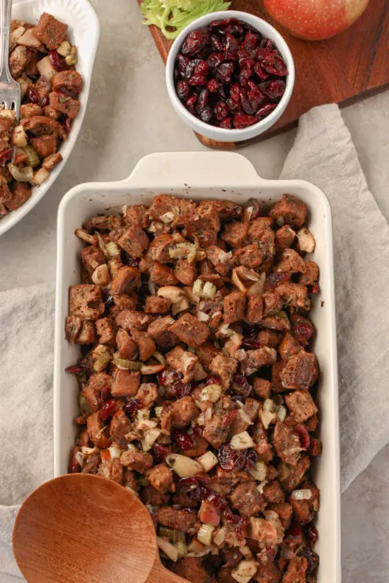 Casserole dish filled with Cranberry Apple Sage Stuffing with serving spoon.