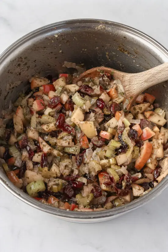 Pot filled with cranberries, chopped apple, celery, onion, and savory herbs and melted butter.
