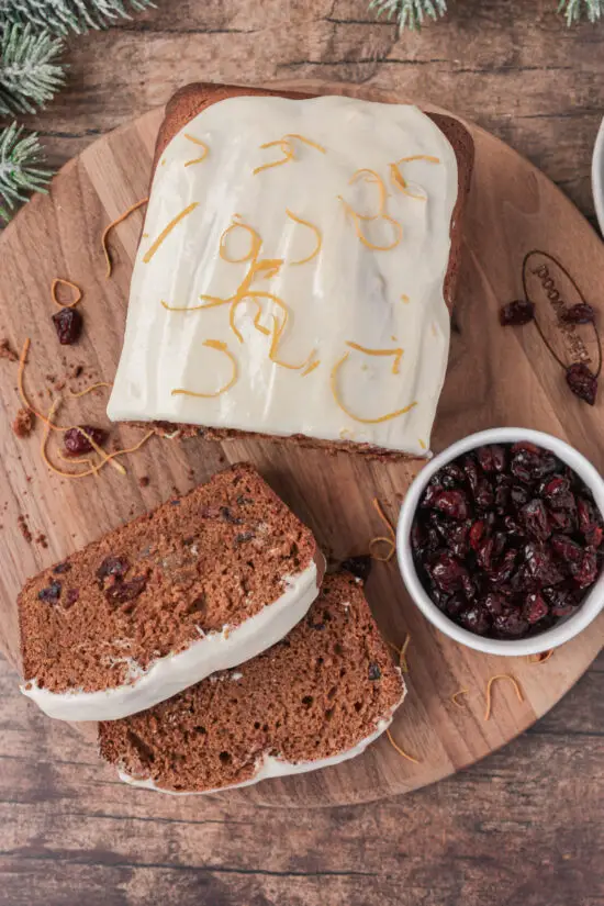 Favorite Old-Fashioned Gingerbread Loaf Recipe on cutting board with two slices and dried cranberries. 