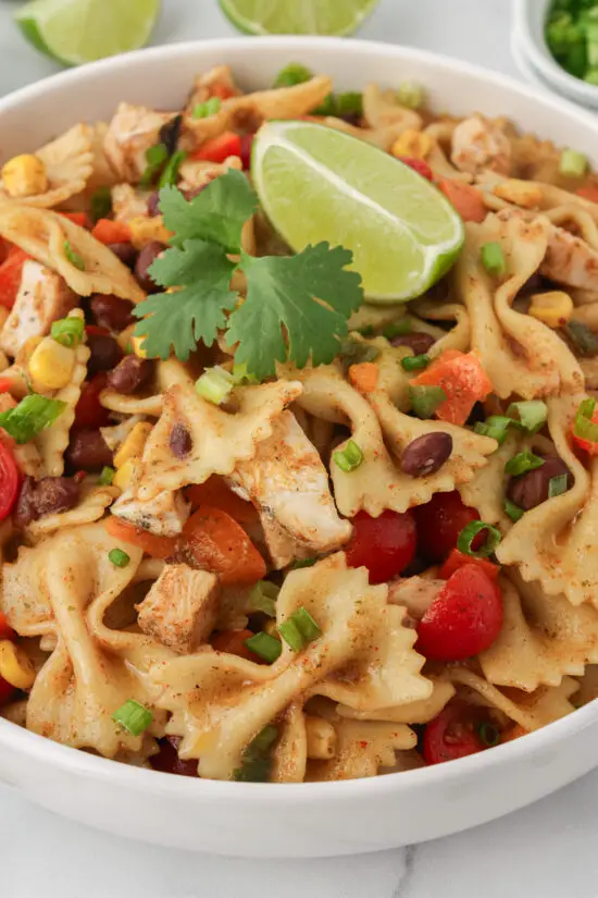 Large bowl of Southwest Chicken Pasta Salad with lime wedge and fresh cilantro. 