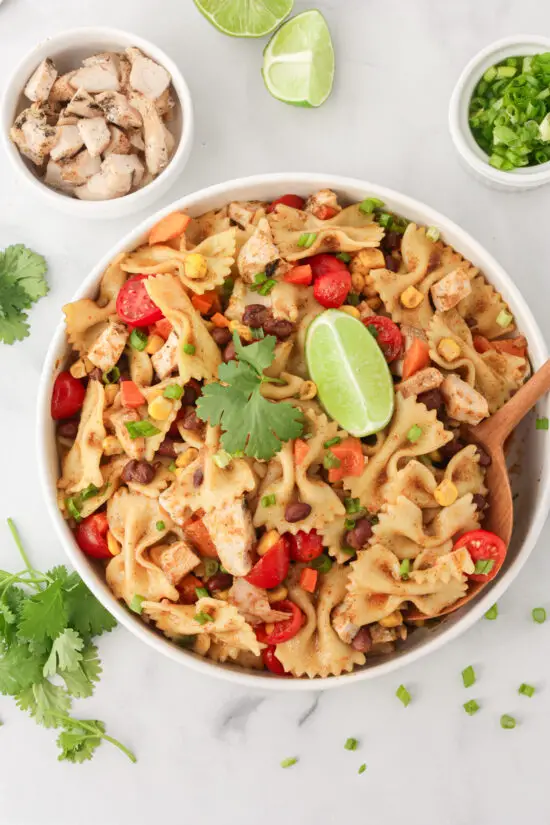 Bowl of Southwest Chicken Pasta Salad with wooden serving spoon and fresh cilantro. 