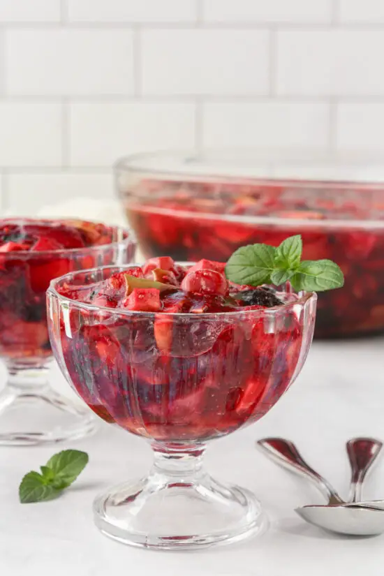 Individual glasses of Easy Raspberry Jello Fruit Salad Recipe with a sprig of mint on top. 